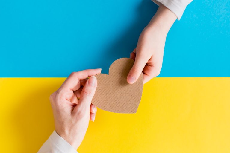 concept-is-no-war-ukraine-childrens-womens-hands-hold-cardboard-heart-against-background-ukrainian-flag-top-view